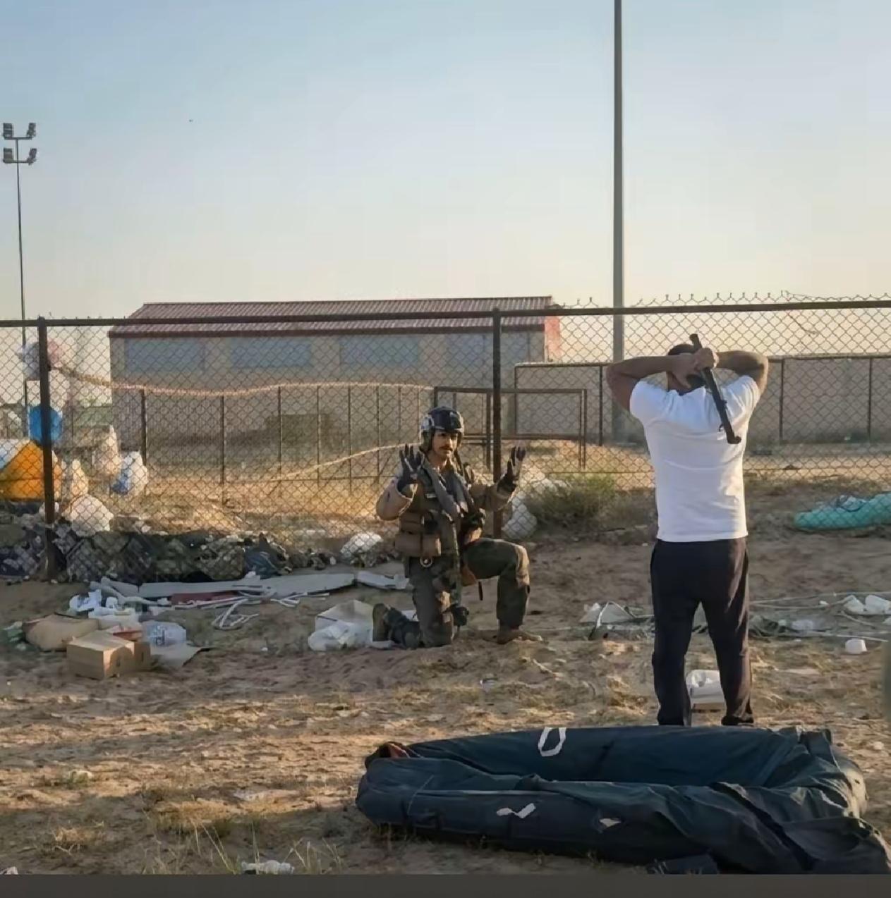 如果说跪地举双手投降的是美军F15战斗机的飞行员，那么站在飞行员对面穿白体恤的人