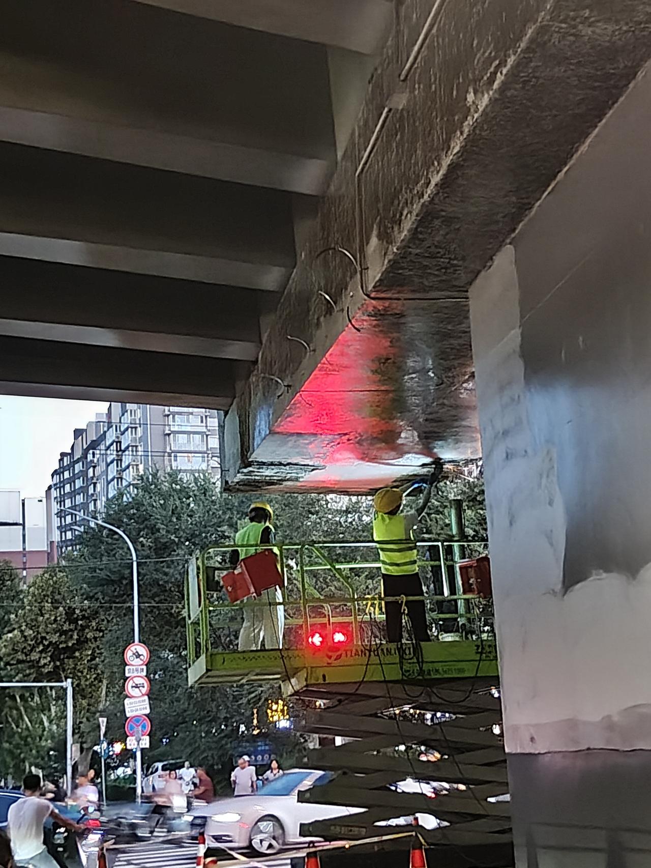 傍晚，立交桥上桥下依旧车流滚滚。路桥工人师傅们，站在升降的作业平台上，抓紧打磨修
