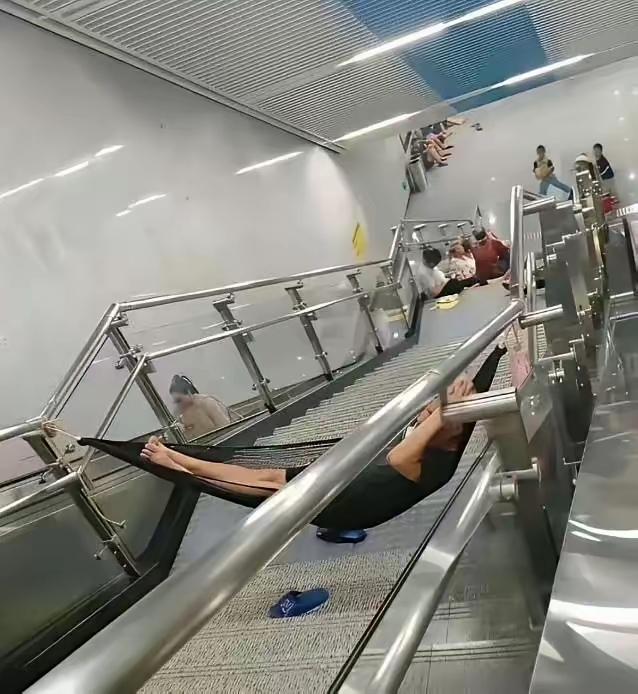 “蹭空调可以，但这样蹭空调就过分了吧！”女子地铁站绑吊床睡大觉，楼梯栏杆当支架，