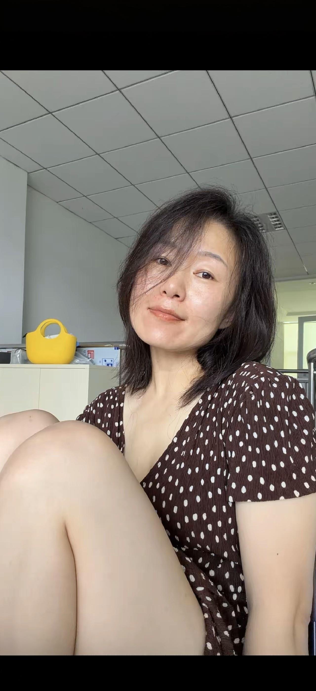 这姑娘坐在办公室里，看着镜头笑。