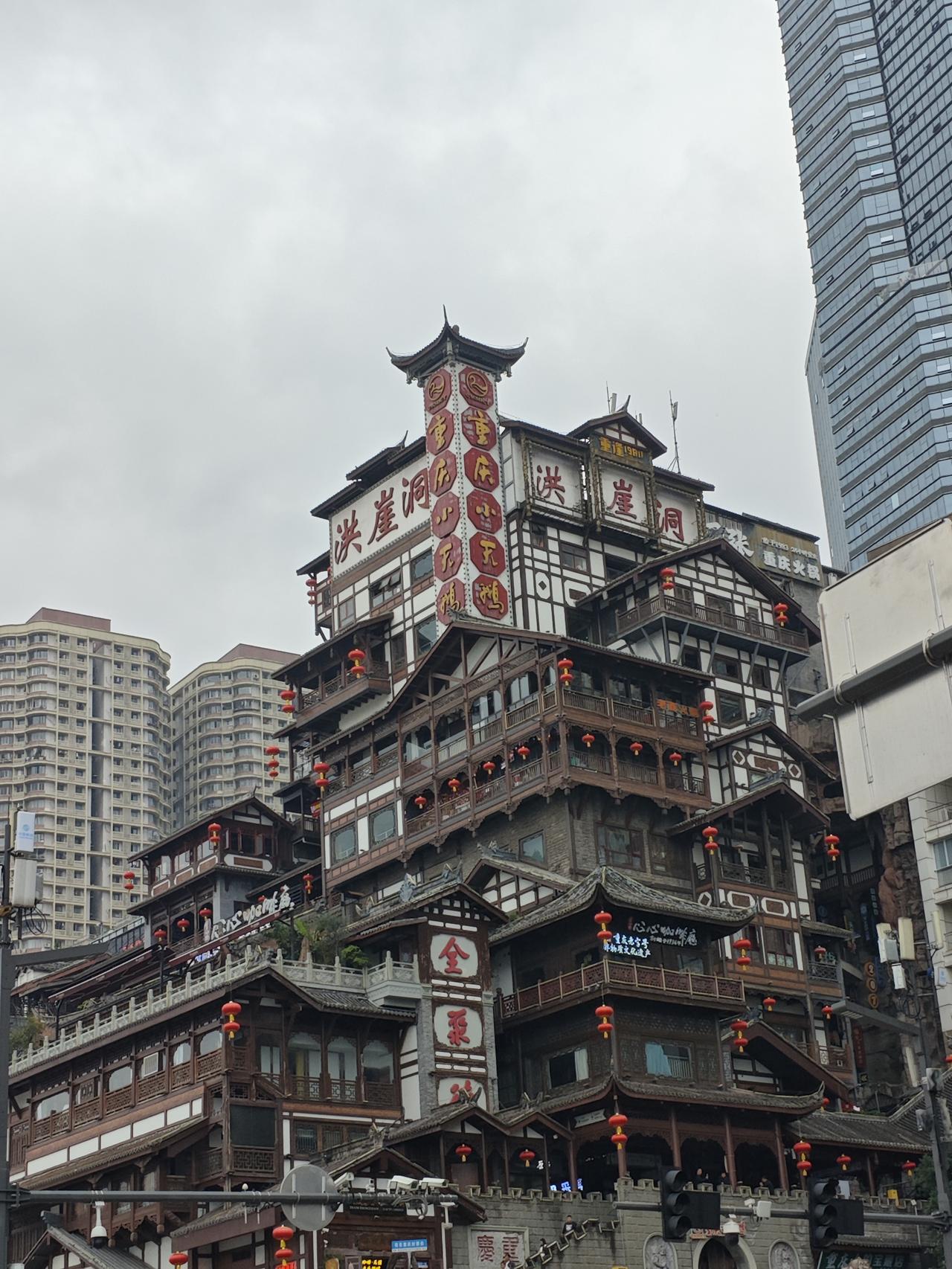 重庆洪崖洞，吊脚楼叠在山城崖壁上，红灯笼串起古意，旁边高楼衬得这“现实版千与千寻