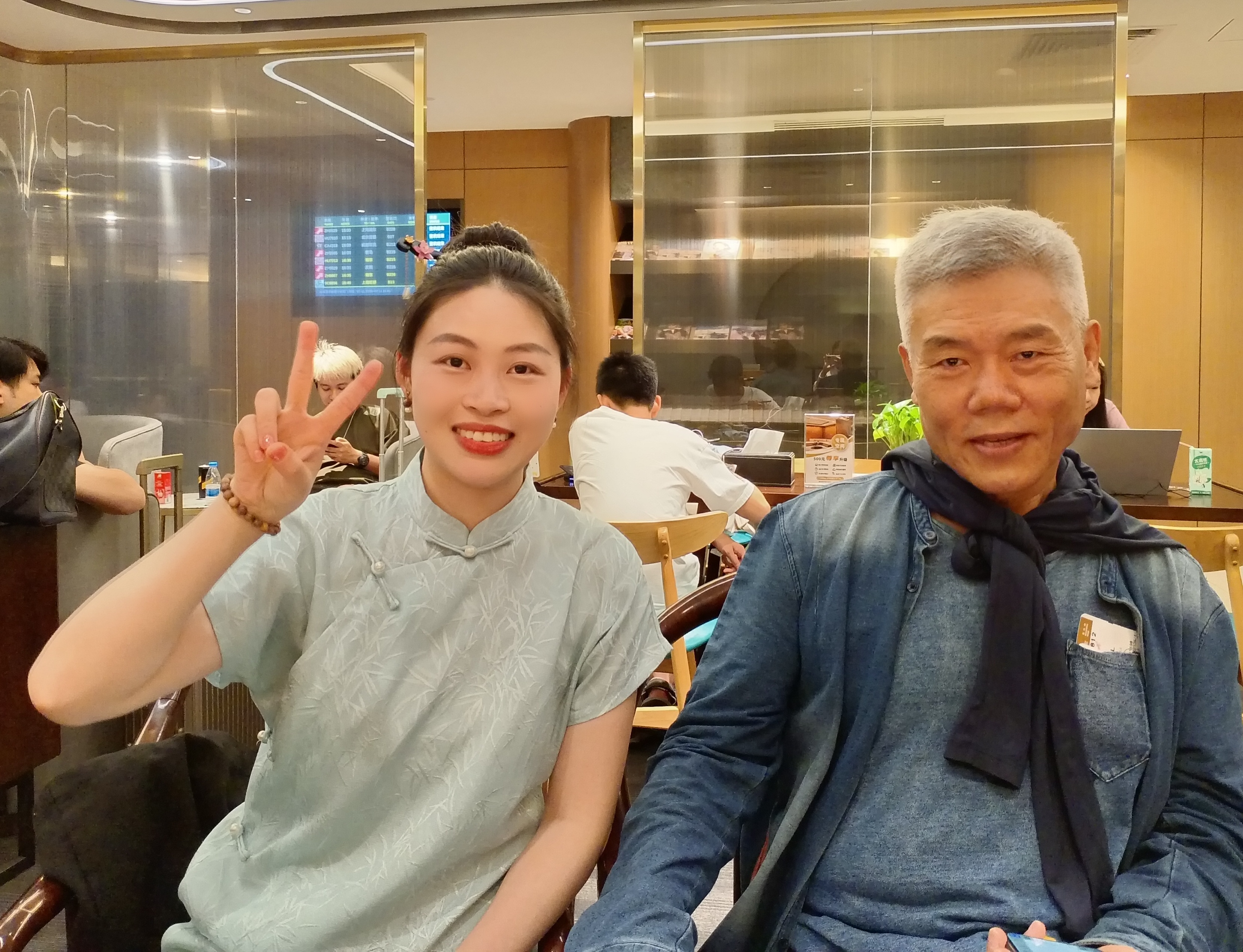 候机楼跟沏茶的姑娘合影。站着跟我合影的姑娘问我喝什么，各种茶都有，白茶离我近，我