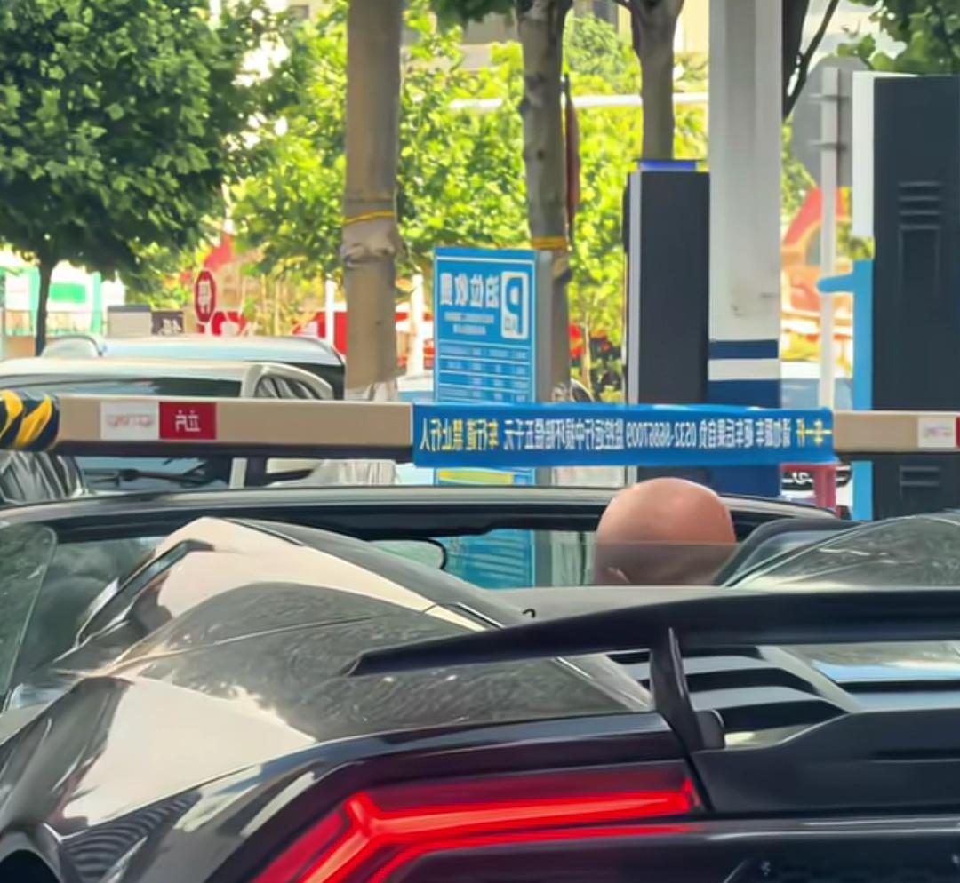 男子开几百万的跑车，为了逃避停车费，出停车场时利用车矮的优势从拦车杆下面钻出。这