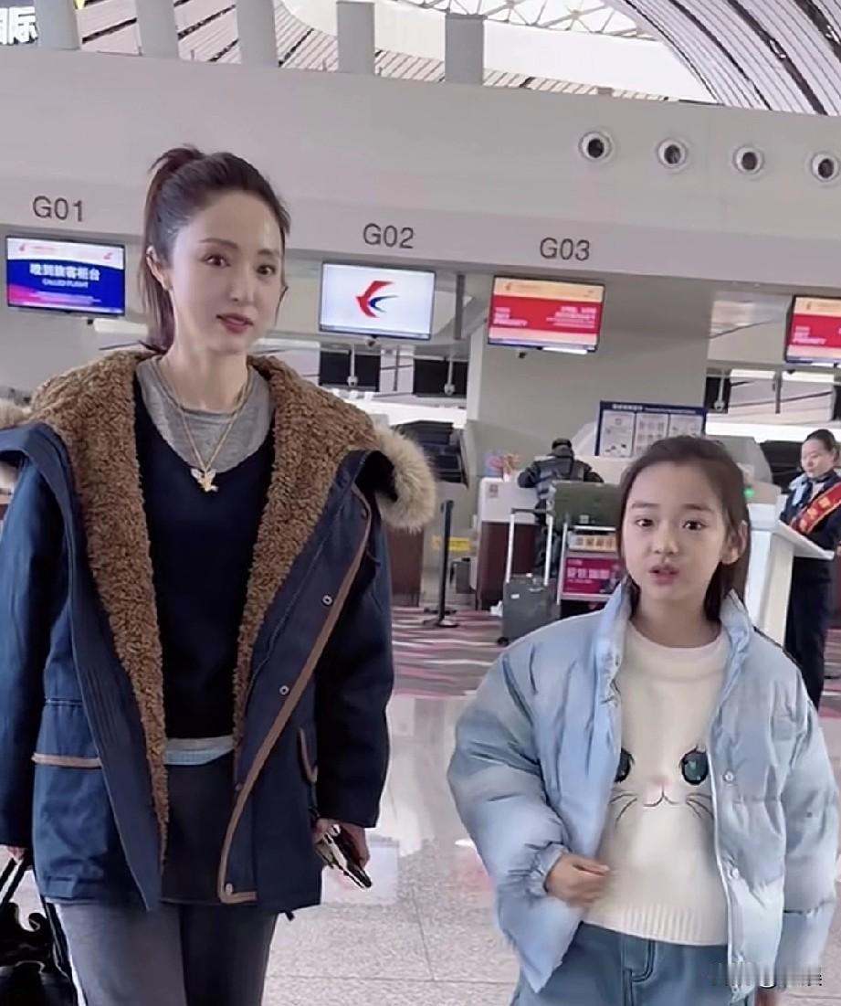 在机场的候机区域，董璇和她的女儿一同亮相，画面温馨。董璇身着带毛绒装饰的深蓝色外
