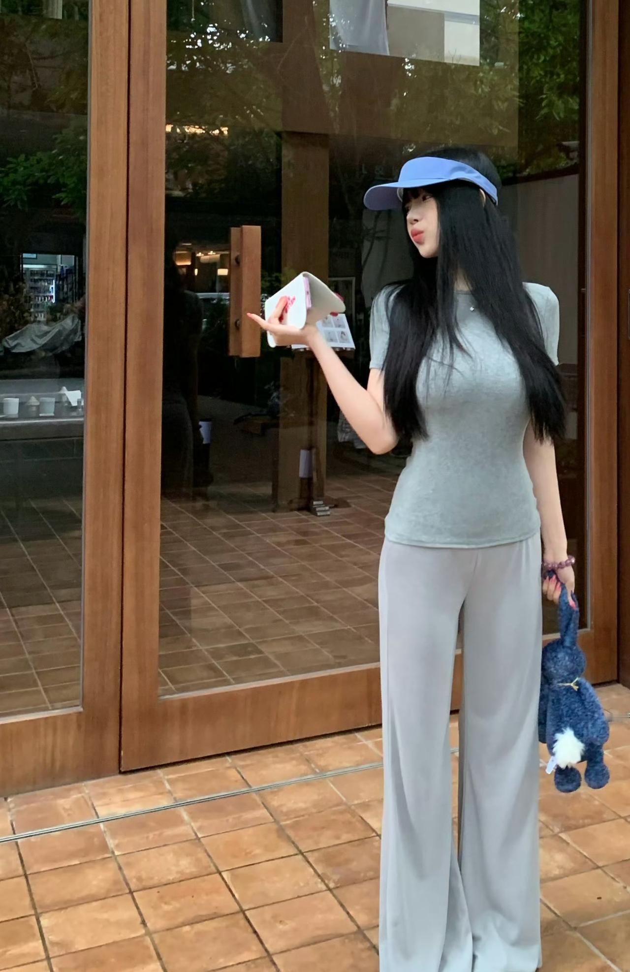 蓝帽配小灰衫，搭配软软的垂感长裤，
抱着可爱小兔玩偶，在复古红砖小店前随性停留。