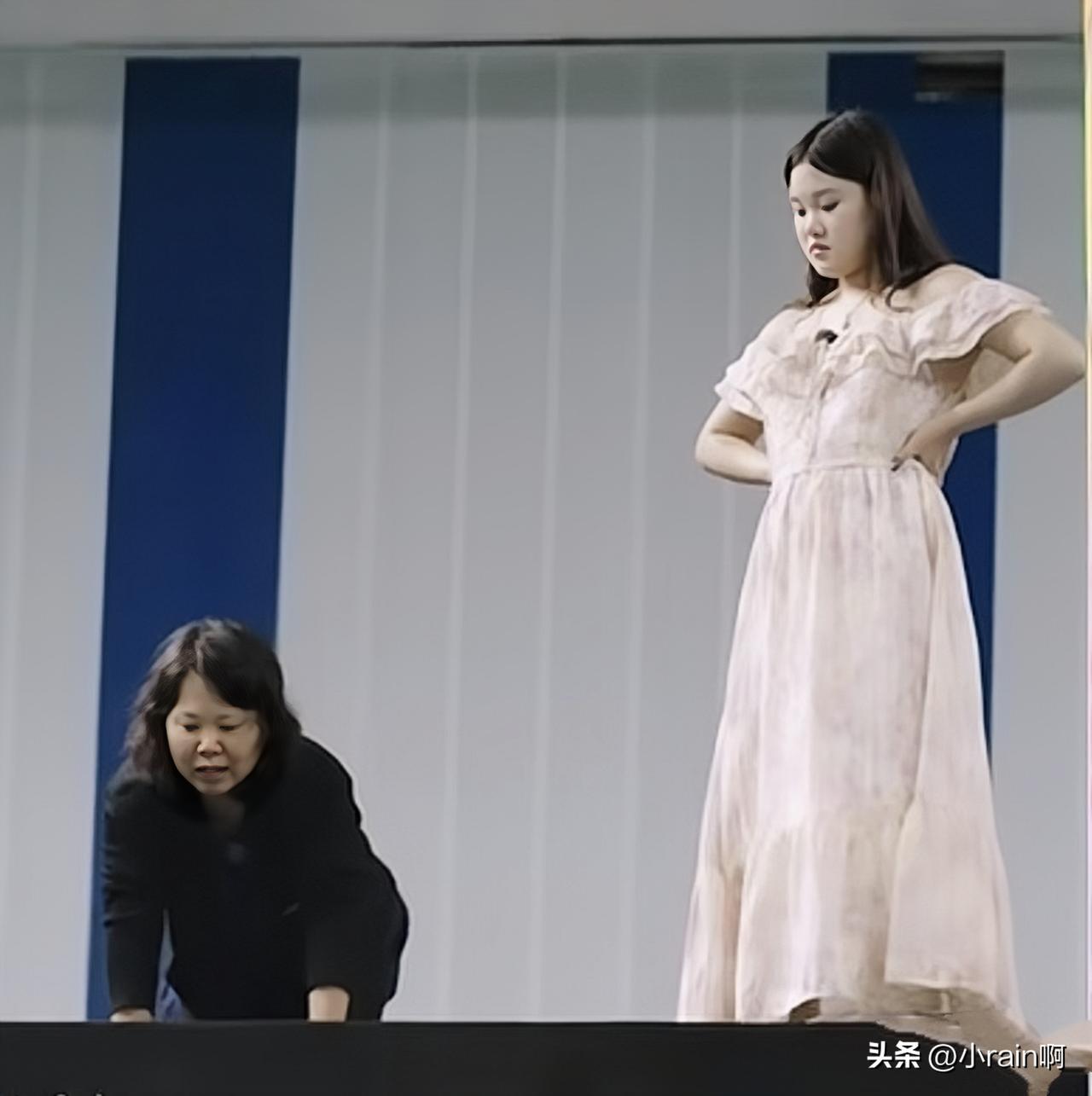 好讽刺的图片。母亲在寻找十几岁的女儿，二十几岁的张家齐在俯视她的表演。你在台上看