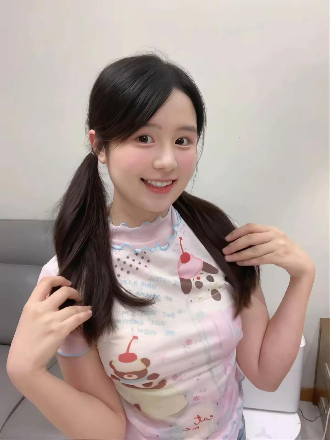 乌黑柔顺的双马尾柔和了脸部线条，脸颊自带淡淡的粉晕，眼神澄澈明亮，笑容清甜又自然