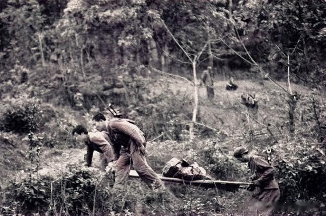 1988年，老山前线，唐道权烈士遗体被战友们抬回国的照片，镜头中的烈士遗体已经残