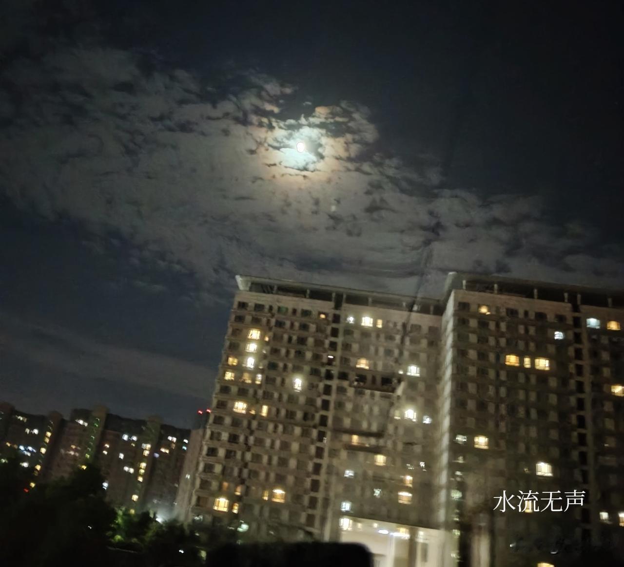 云揽清辉，月华穿过层叠的云絮，在墨色的夜空晕开一圈温柔光晕，缓缓落向林立的楼宇。