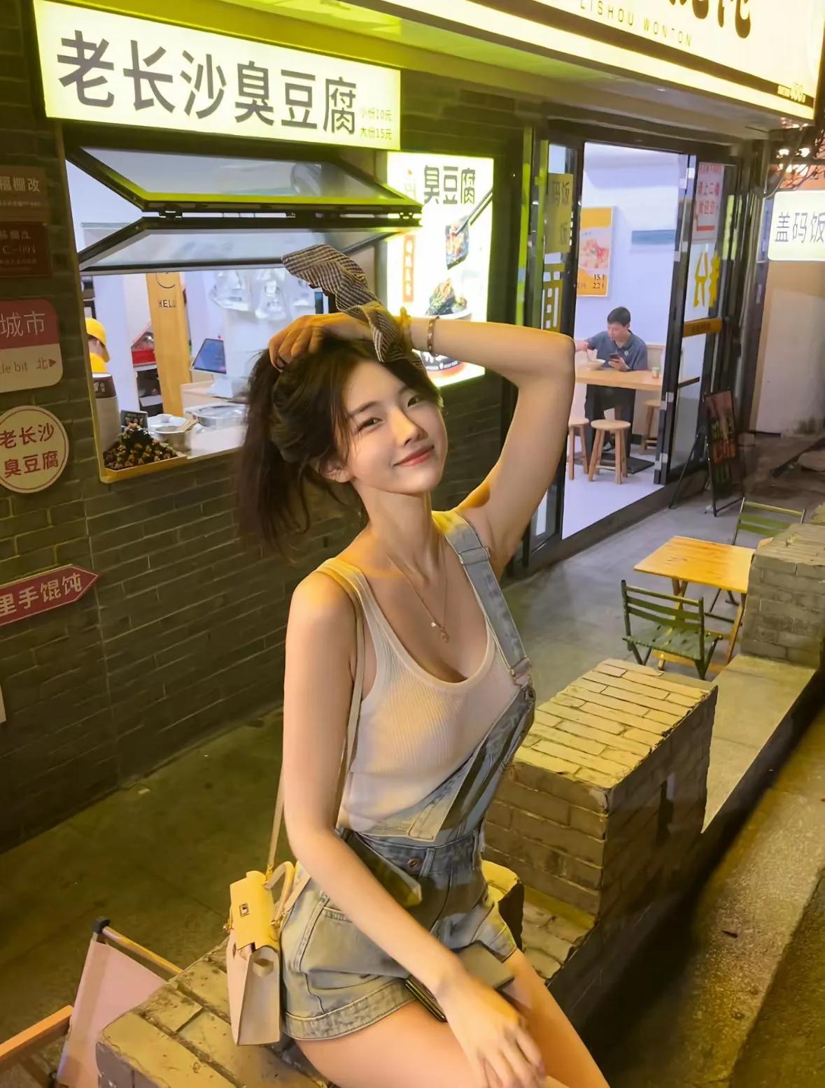 这位小姐姐在街边小店门口自拍，笑容甜美。