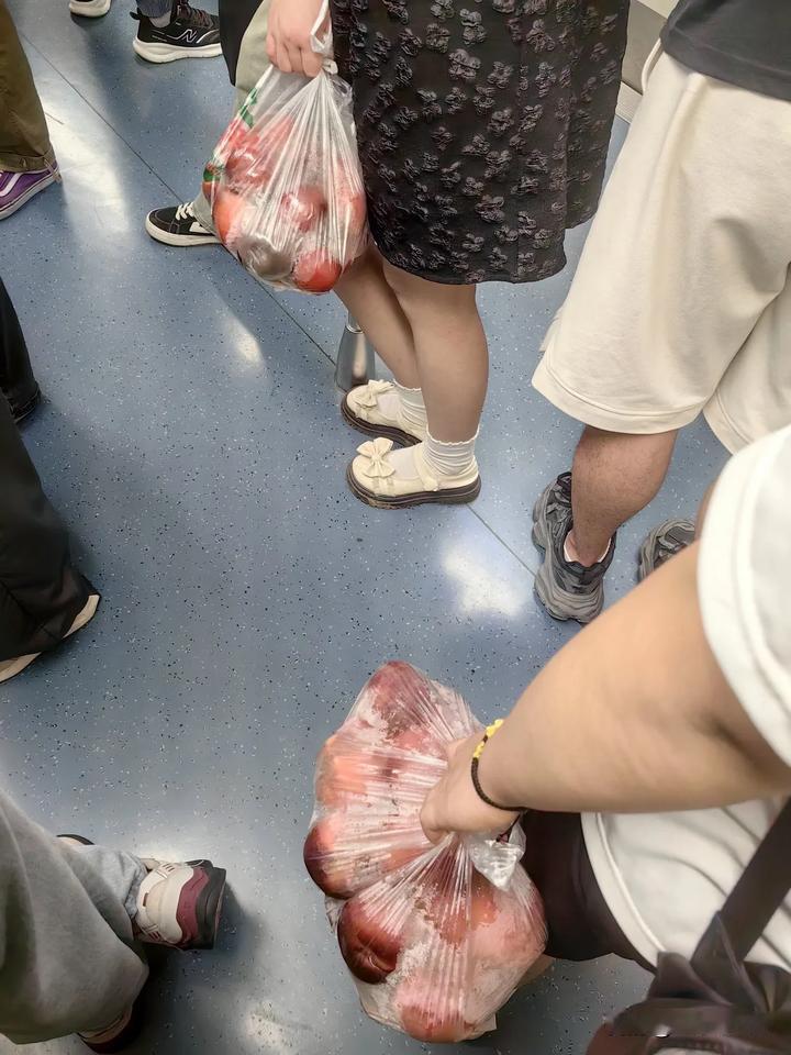 这对年轻男女，拎的都是苹果，但他们却是分开的，男子倚靠着车厢壁，看起来有些疲乏的