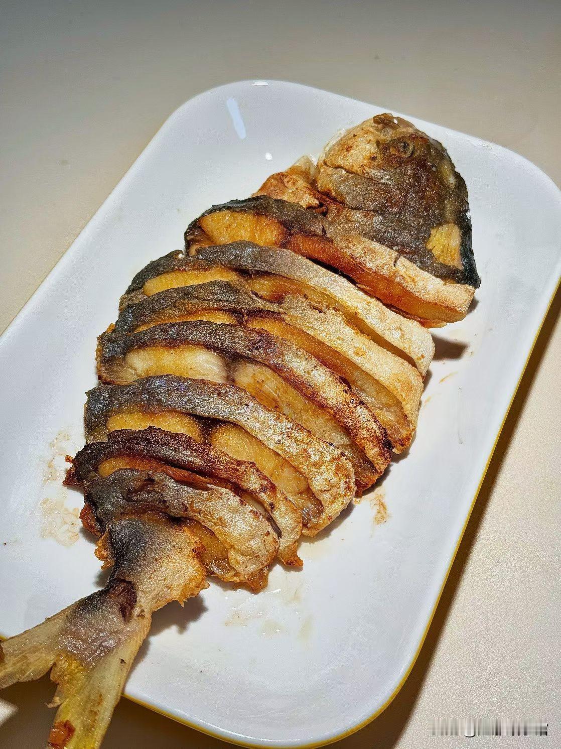 今早突发奇想，把冰箱里冻了半周的金鲳鱼拎出来，改刀成“风琴状”下锅煎。
 
热油