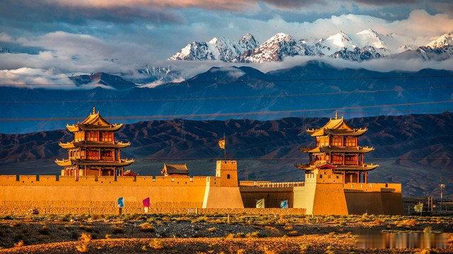 河西咽喉嘉峪关一座雄关守千年当落日缓缓垂落戈壁，暖金色霞光铺满嘉峪关的夯土城墙，