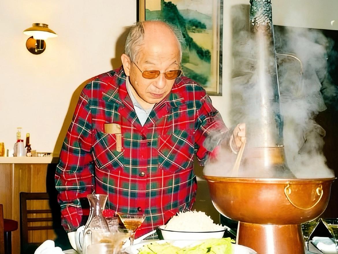 1988年，87岁的张学良在寓所内涮火锅时的照片，镜头中的他正起身，从热气腾腾的