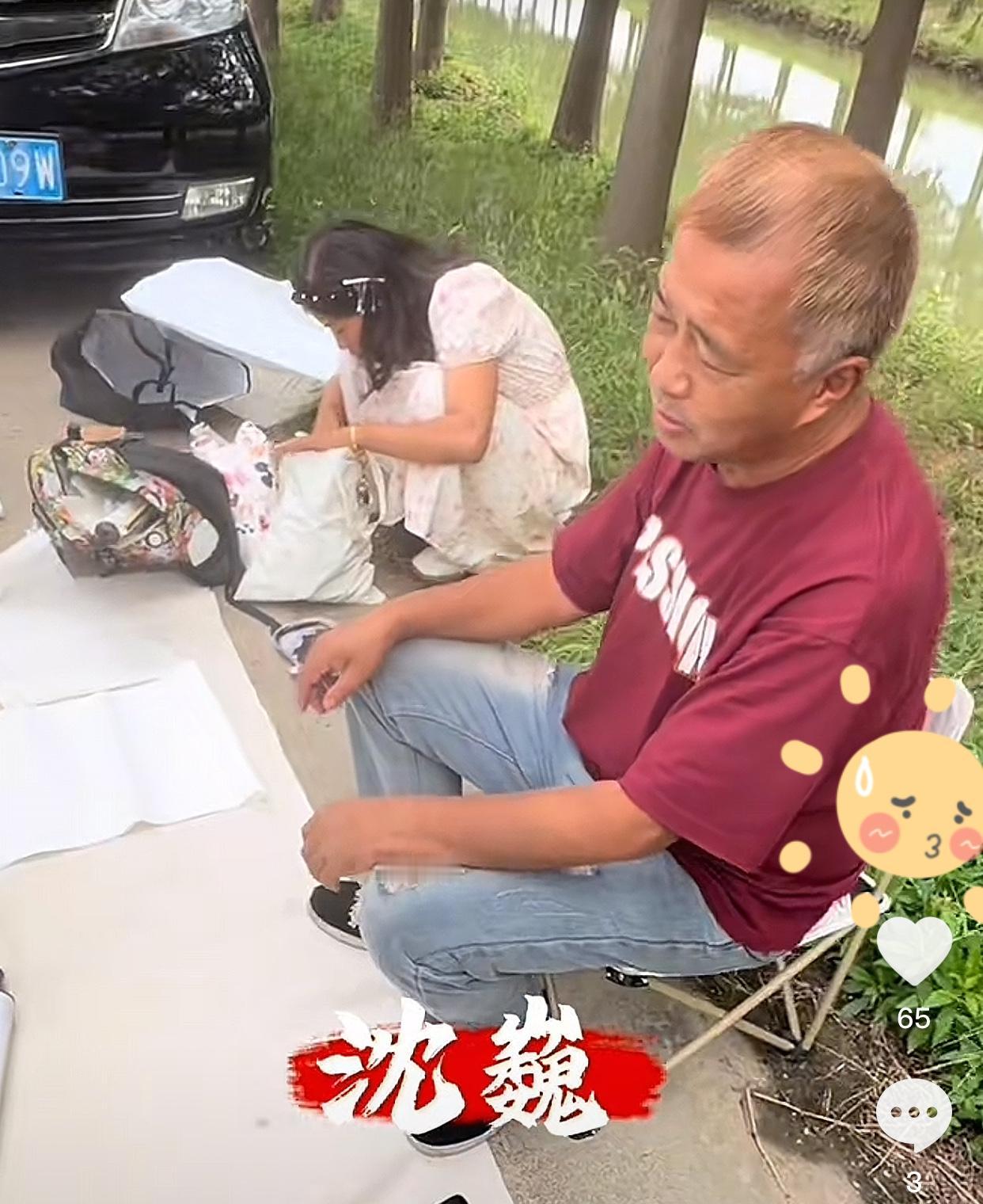 沈巍找到了一个小河边的地方，10月4日他以地为桌，坐着小凳子，开摊写字画了。众主