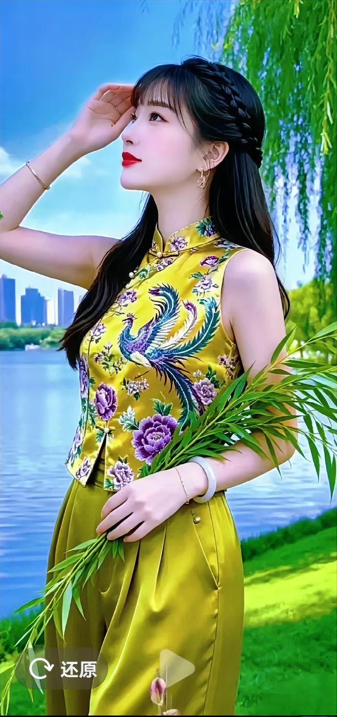 湖畔微风拂过柳枝，一袭鎏金新中式套装格外亮眼。衣身凤凰与牡丹刺绣精致夺目，把东方