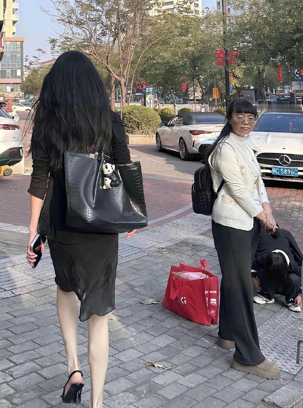 同样是女人，穿衣打扮差别大

图片中两个女人擦肩而过。左边的女人，长发及腰，身材