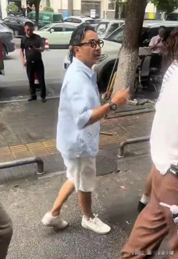 著名主持人汪涵和沈梦辰现身街头，汪涵老师头发花白凌乱，穿着浅蓝色衬衫，白色短裤，