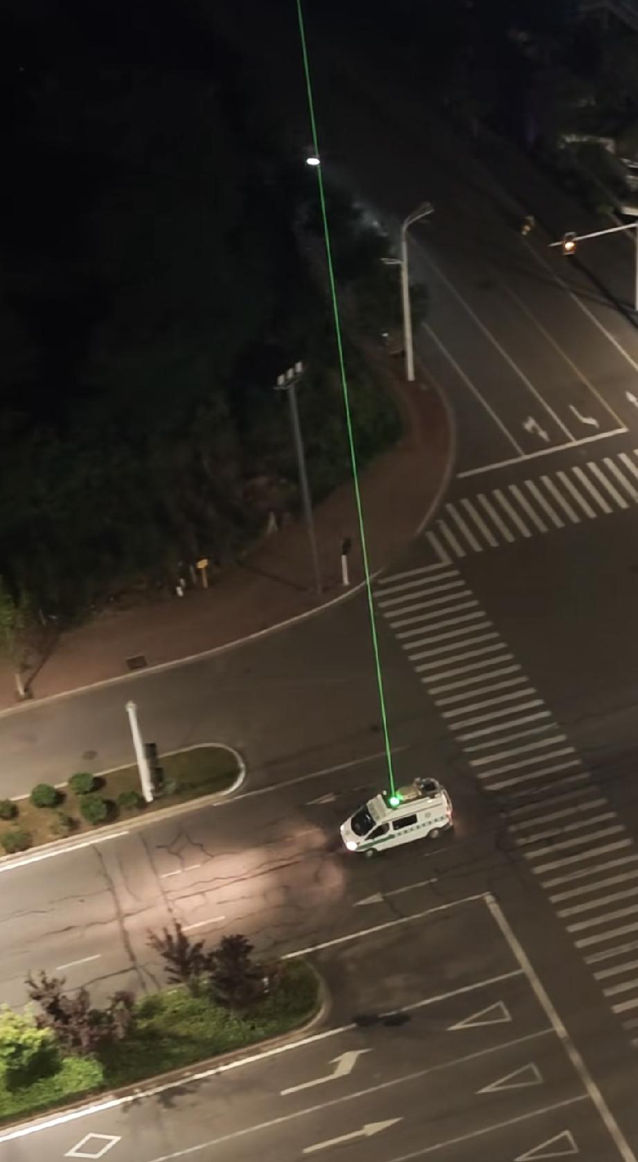 一辆小巴车，车顶上装着绿色的激光光源设备，就这是这样来回的悠转，这光束线都能照得