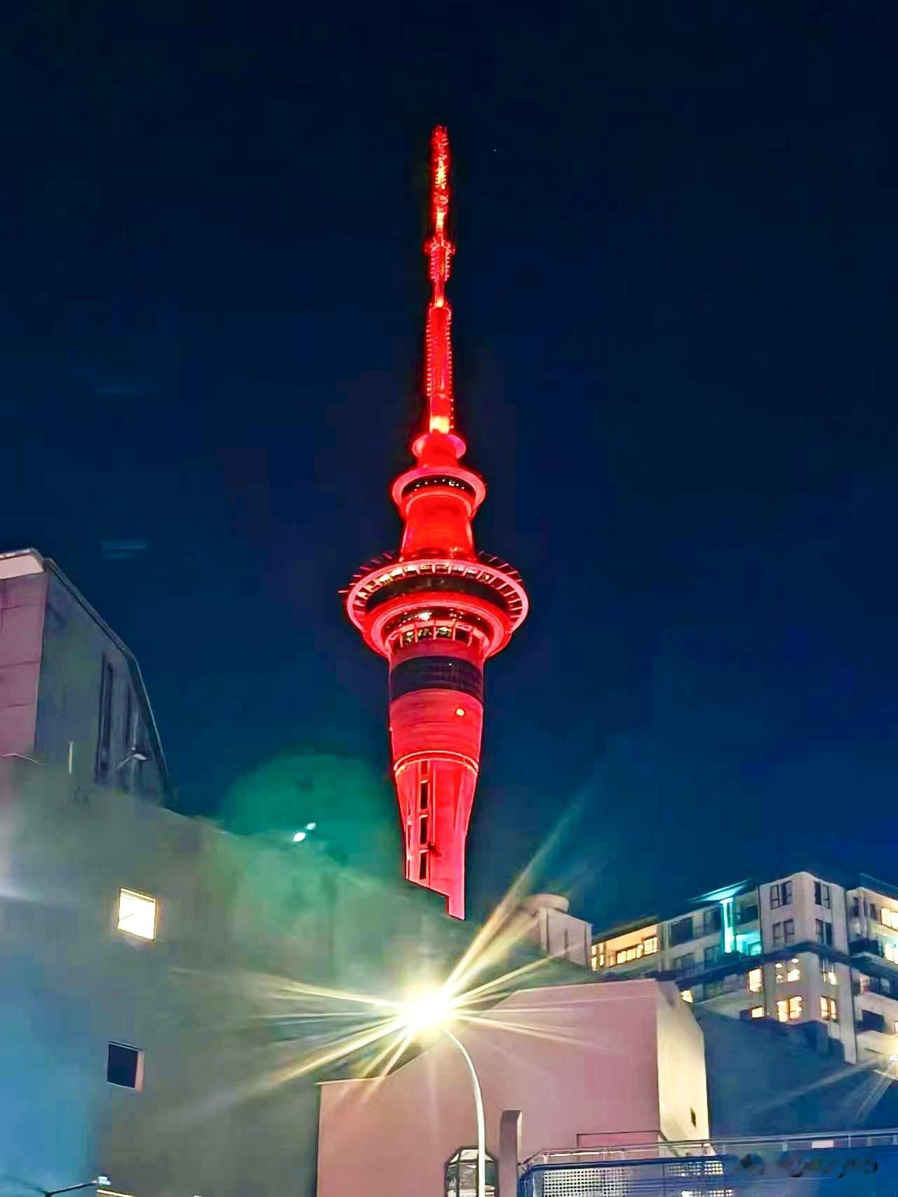 夜色笼罩奥克兰，赤红天空塔拔地而立，灯火璀璨勾勒城市浪漫轮廓。

奥克兰天空塔是