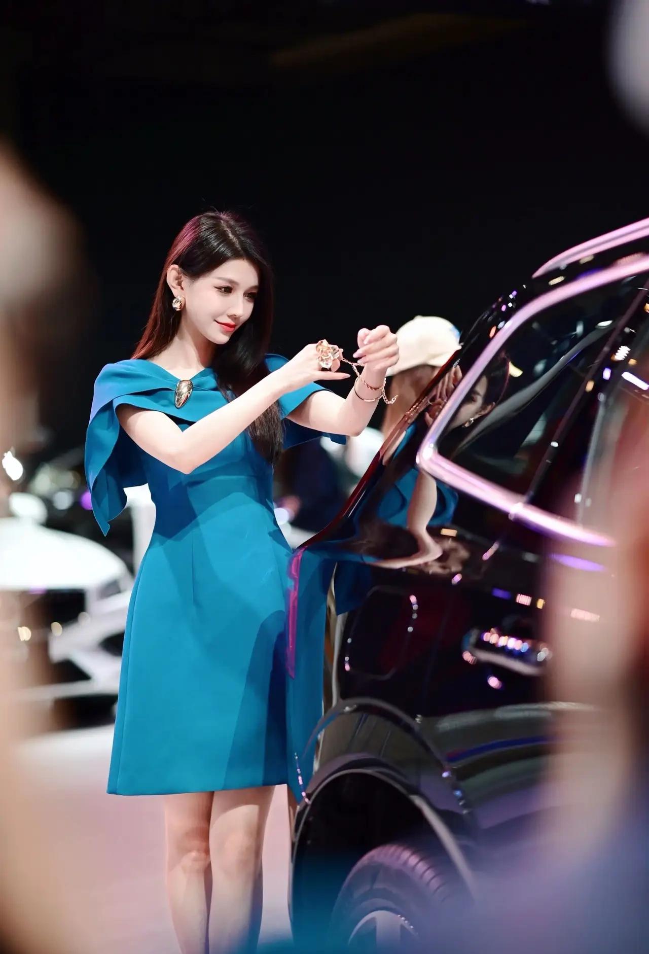 《车展上的蓝色魅力》
在灯光璀璨的车展大厅里，一位身着蓝色连衣裙的女模特优雅地站