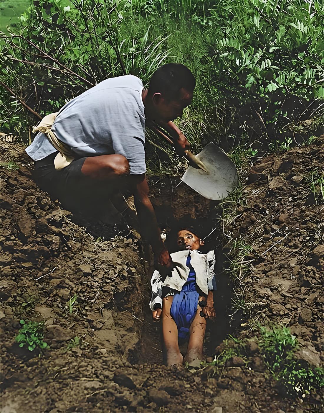 1946年，湖南，一名男子身着破旧的浅色短袖，蹲在简陋的土坑旁，手持铁锹，正准备