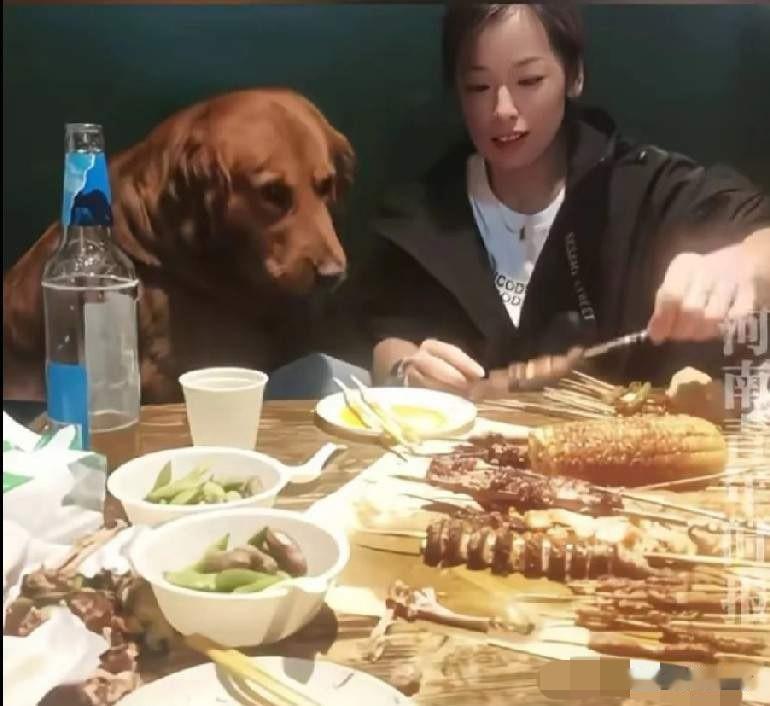5月10日大连市金州区一个烧烤店内，一女子在餐桌上喂狗子肉串！

女子坐在体型庞