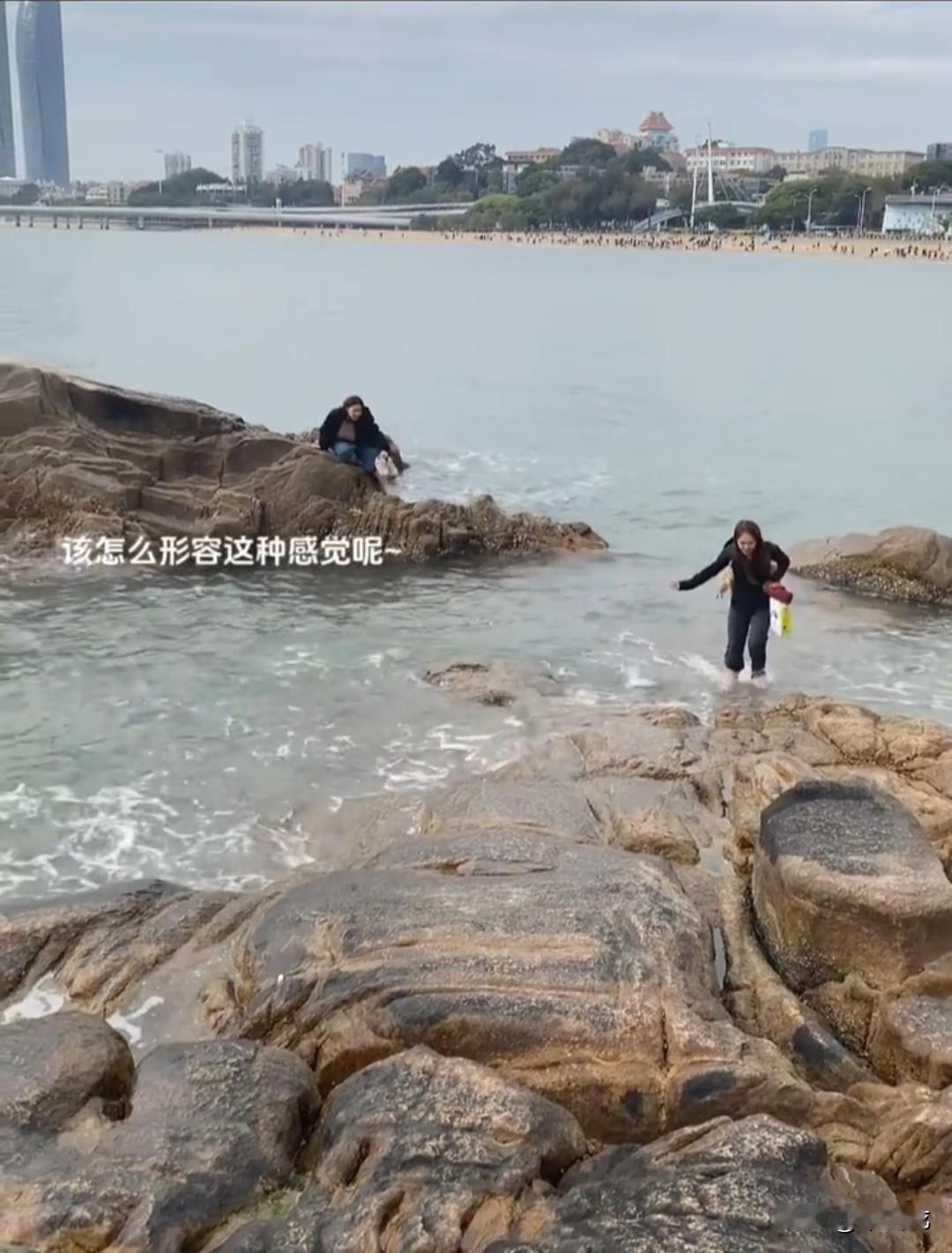 两名女子站在海边礁石上拍照，没料想海水突然间涨了起来，其中一人趁着涨潮幅度不大，