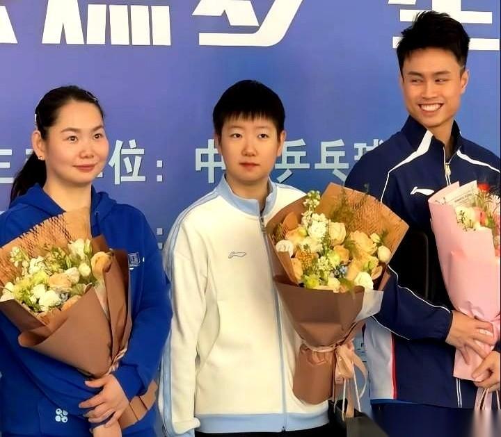 这画面真有点意思。
孙颖莎一个人站C位，旁边齐刷刷一排国乒男将，周启豪、徐瑛彬、
