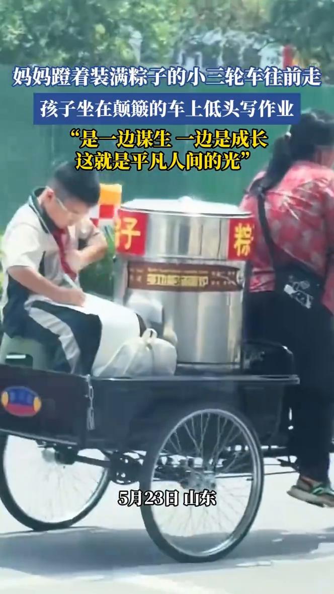 妈妈蹬着装满粽子的小三轮车往前走，孩子坐在颠簸的车上低头写作业。"是一边谋生一边