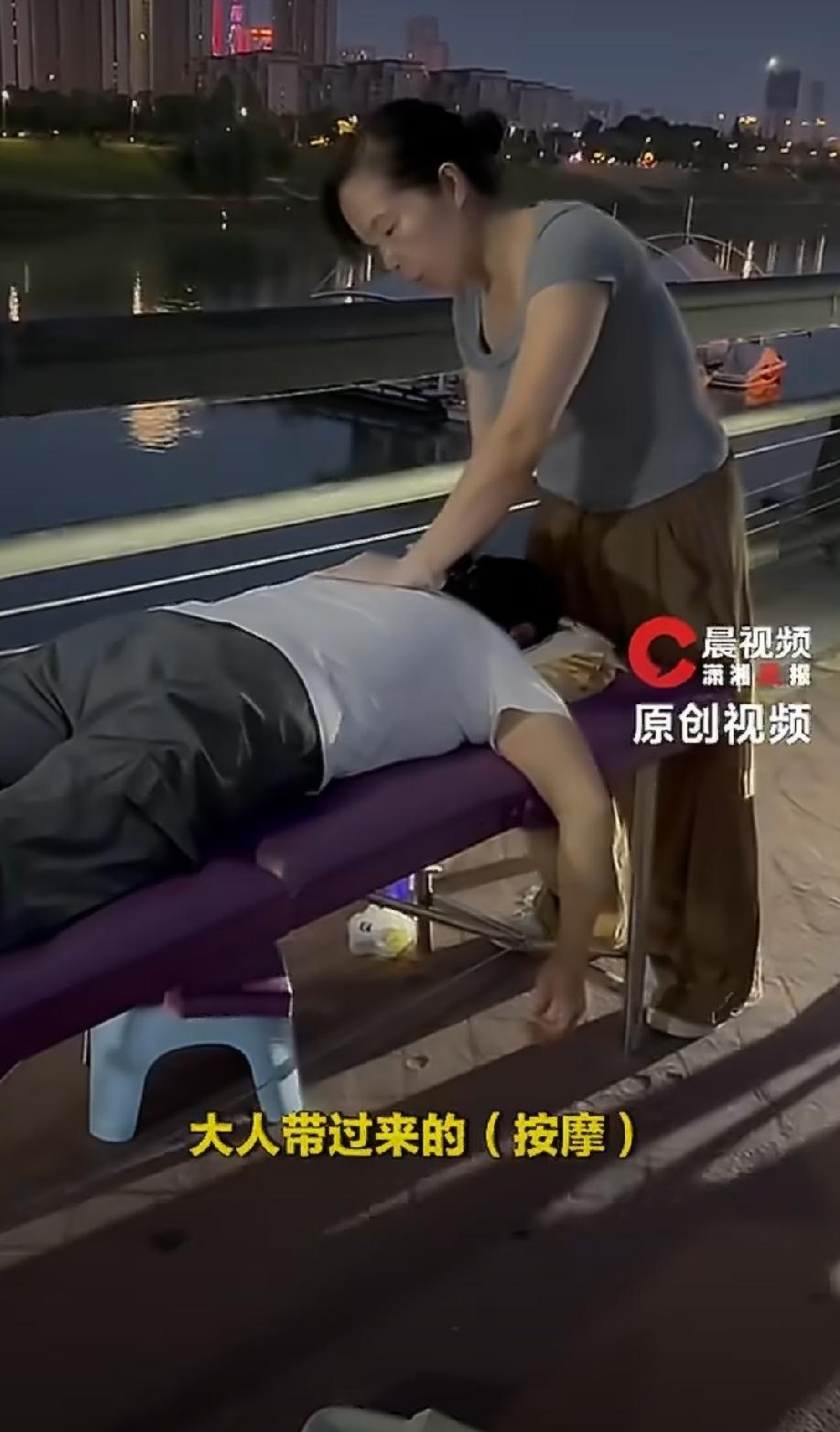 长沙浏阳河边，最近出了个新鲜事。

一位38岁的大姐，支了张简易床，挂上块“按摩