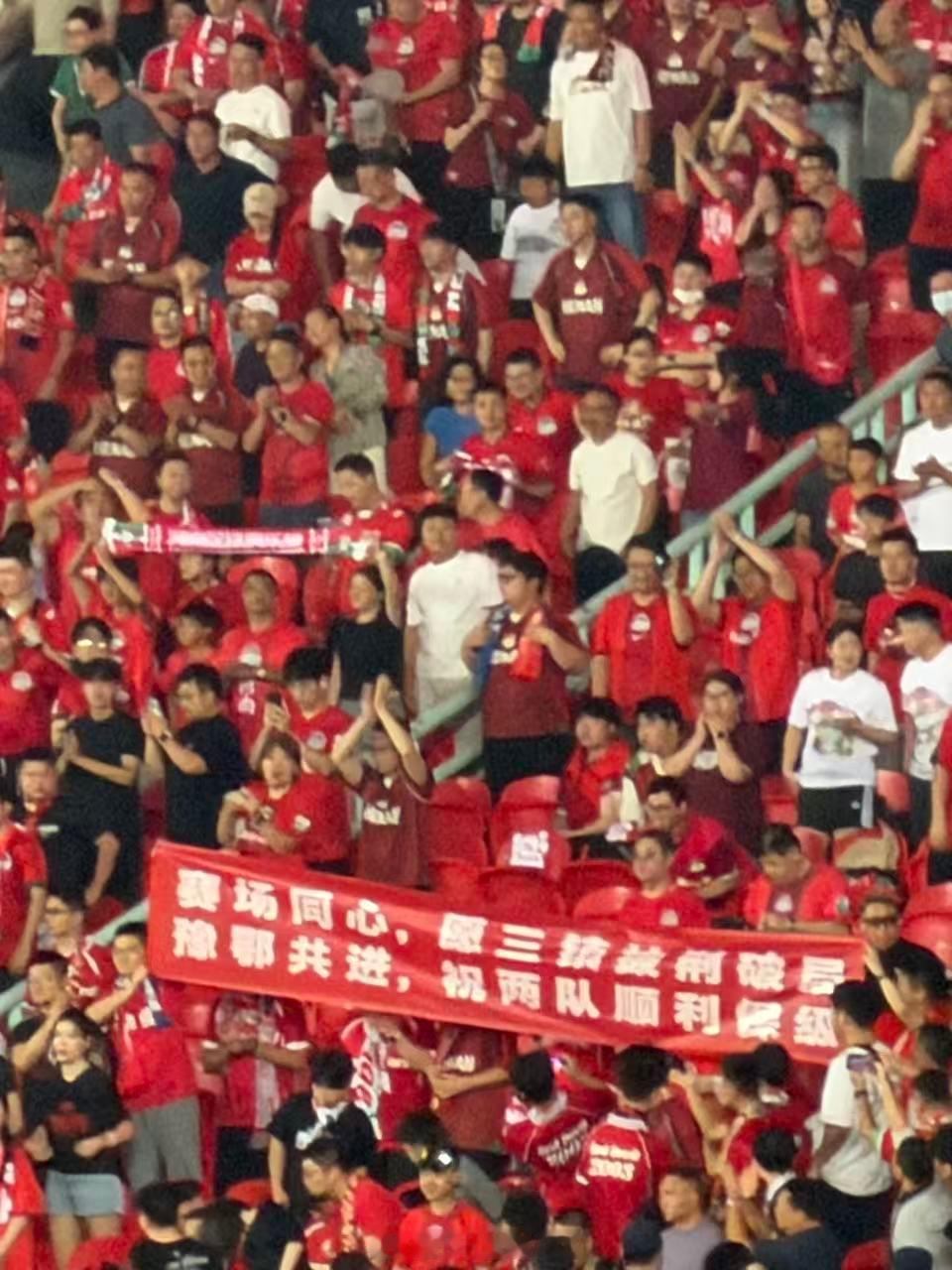 武汉三镇vs河南队 河南球迷远征军看台展示条幅祝福武汉三镇“赛场同心，愿三镇披荆