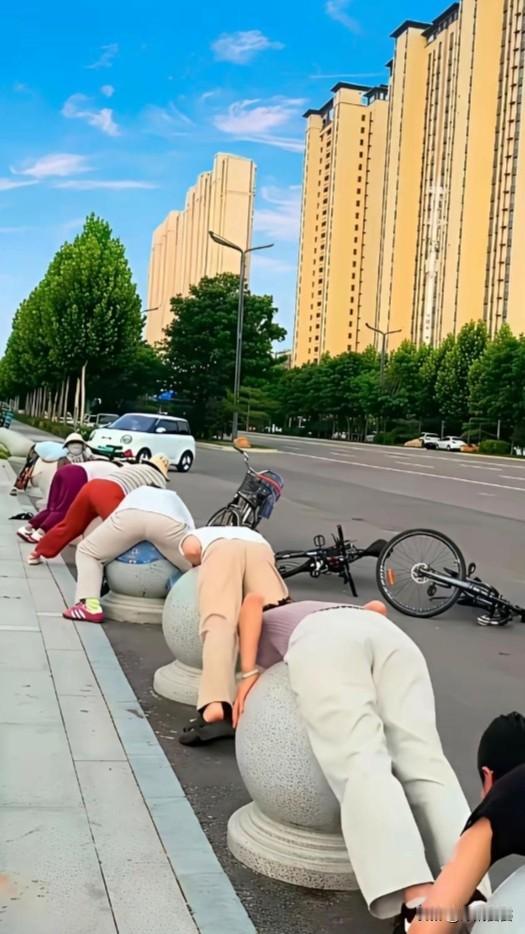 这些大姐大妈不是练功，是流行的民间土养生——石疗（天灸热疗）。
夏天太阳把石墩晒