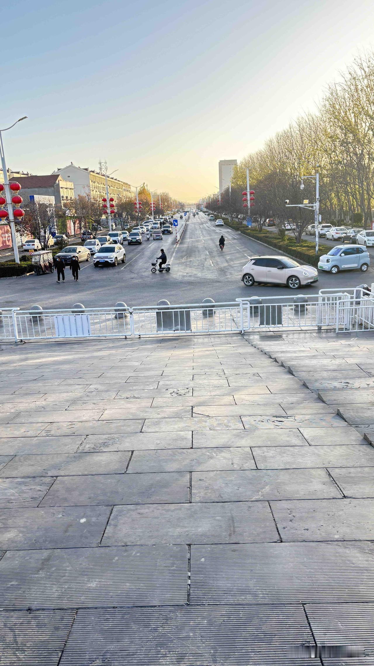 这早上的街可真热闹！太阳刚露头，马路上车都排上队了，小电驴“嗖”地从缝里钻过去。