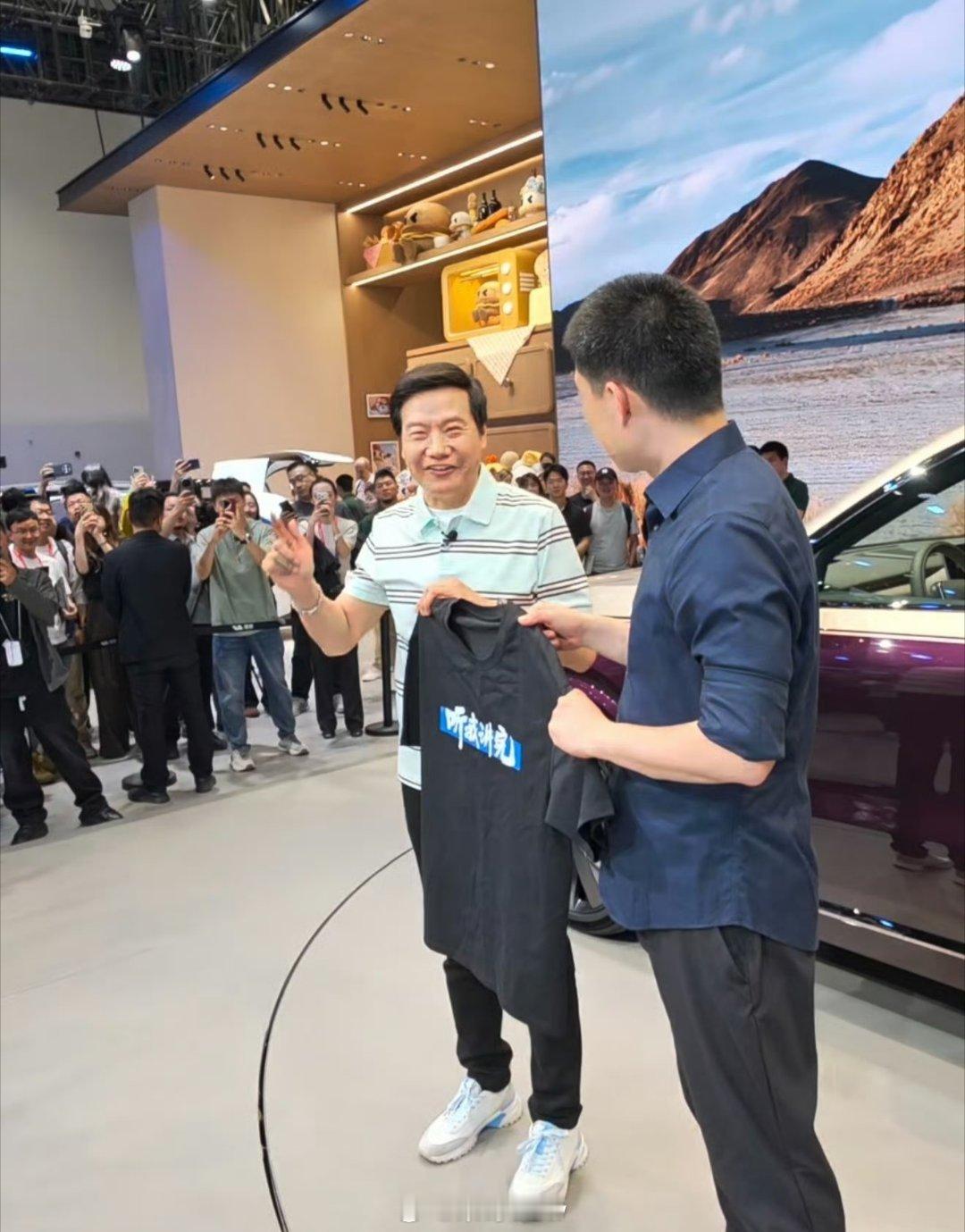 雷军现场给李想送上专属“听我讲完”T恤，李想笑着礼貌回一句谢谢，互动也太有意思了