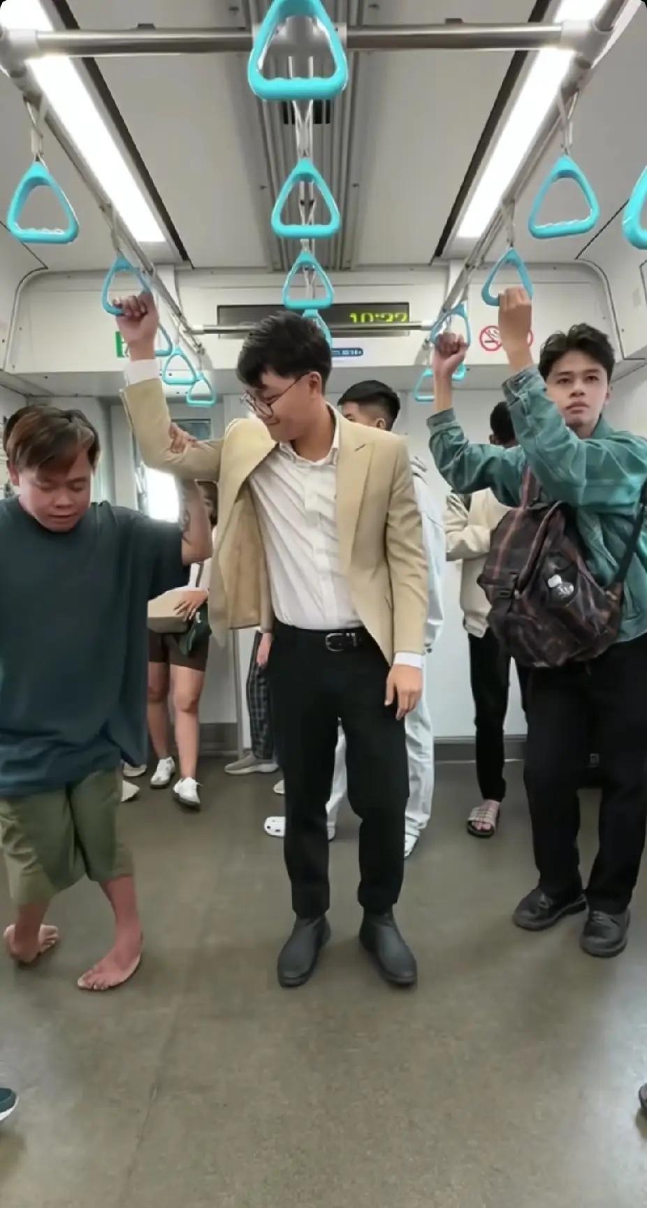 地铁上，残疾小伙子有些费劲地拉着吊环，站在旁边的陌生男子看了看后，突然伸出了一只