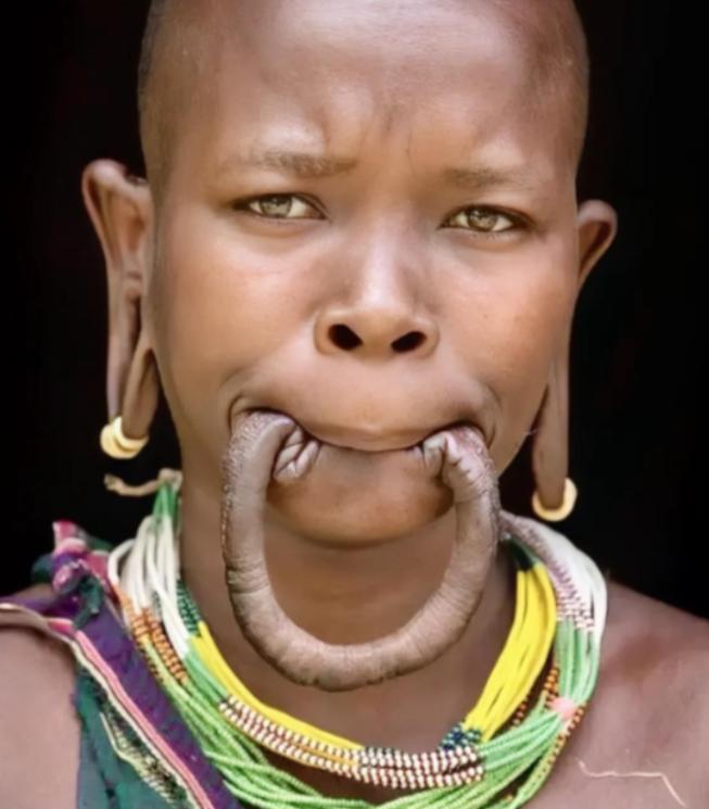 这是一名漂亮的非洲“唇盘族”女孩，她嘴里含着的并不是香肠，而是自己的下嘴唇，女孩