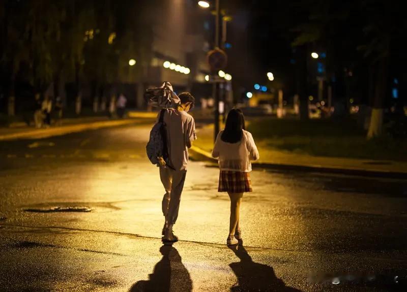 女生想让你追她会有哪些暗示呢? 一对情侣在夜晚散步，路灯下显得很温馨。