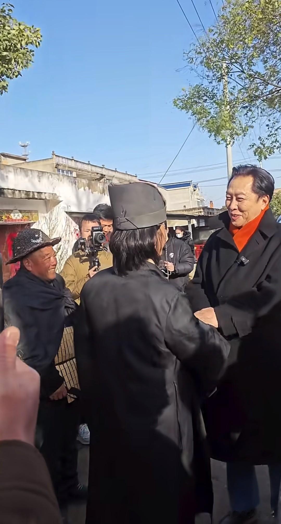 唐国强到村里探望土味三国导演鲍小光。在村口两人亲切握手，再往村里边走边聊，看拍摄