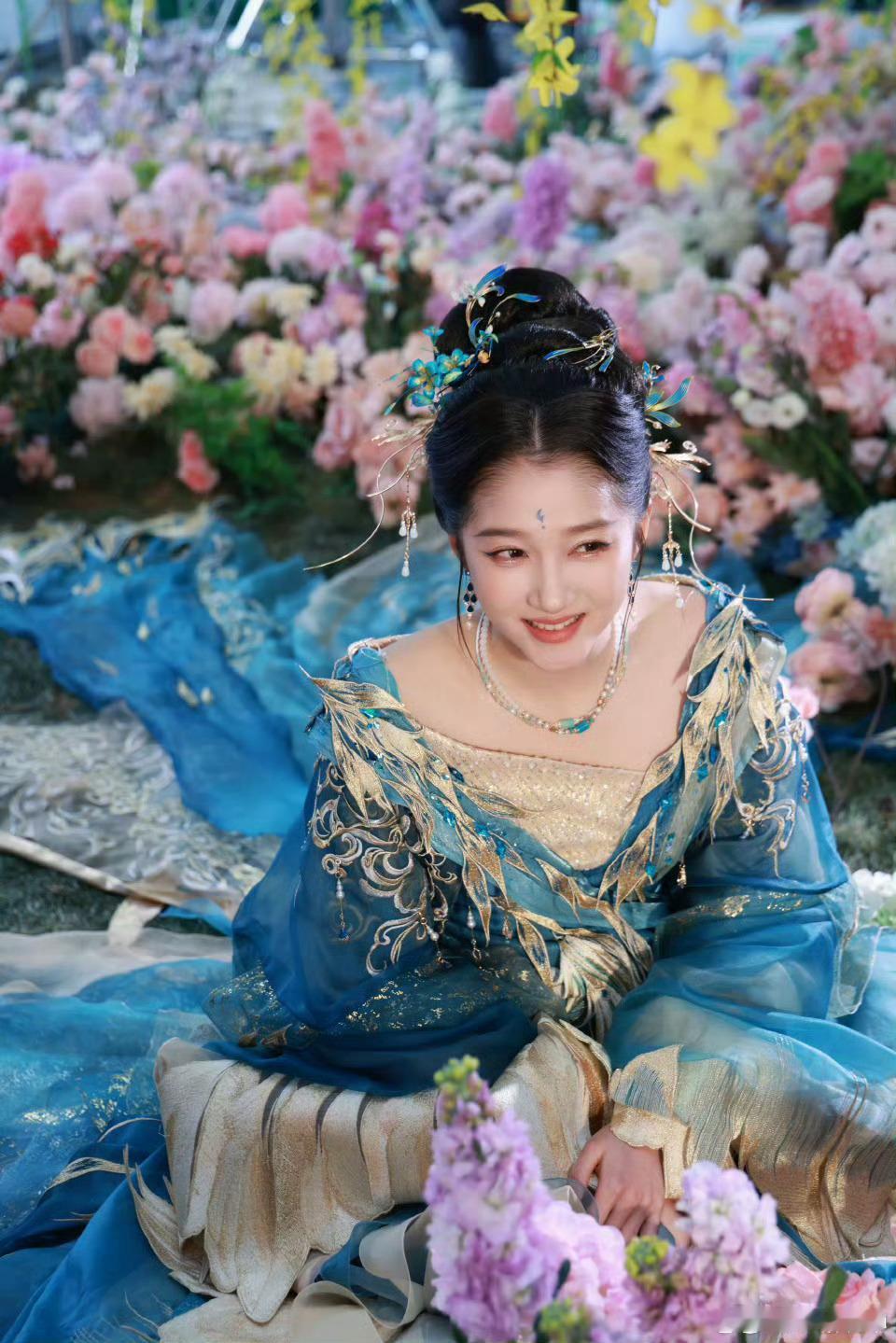 关晓彤青金羽衣落尘寰，繁花漫野映清颜。眉眼含春，衣袂翩跹，似从千年画卷中走来的仙