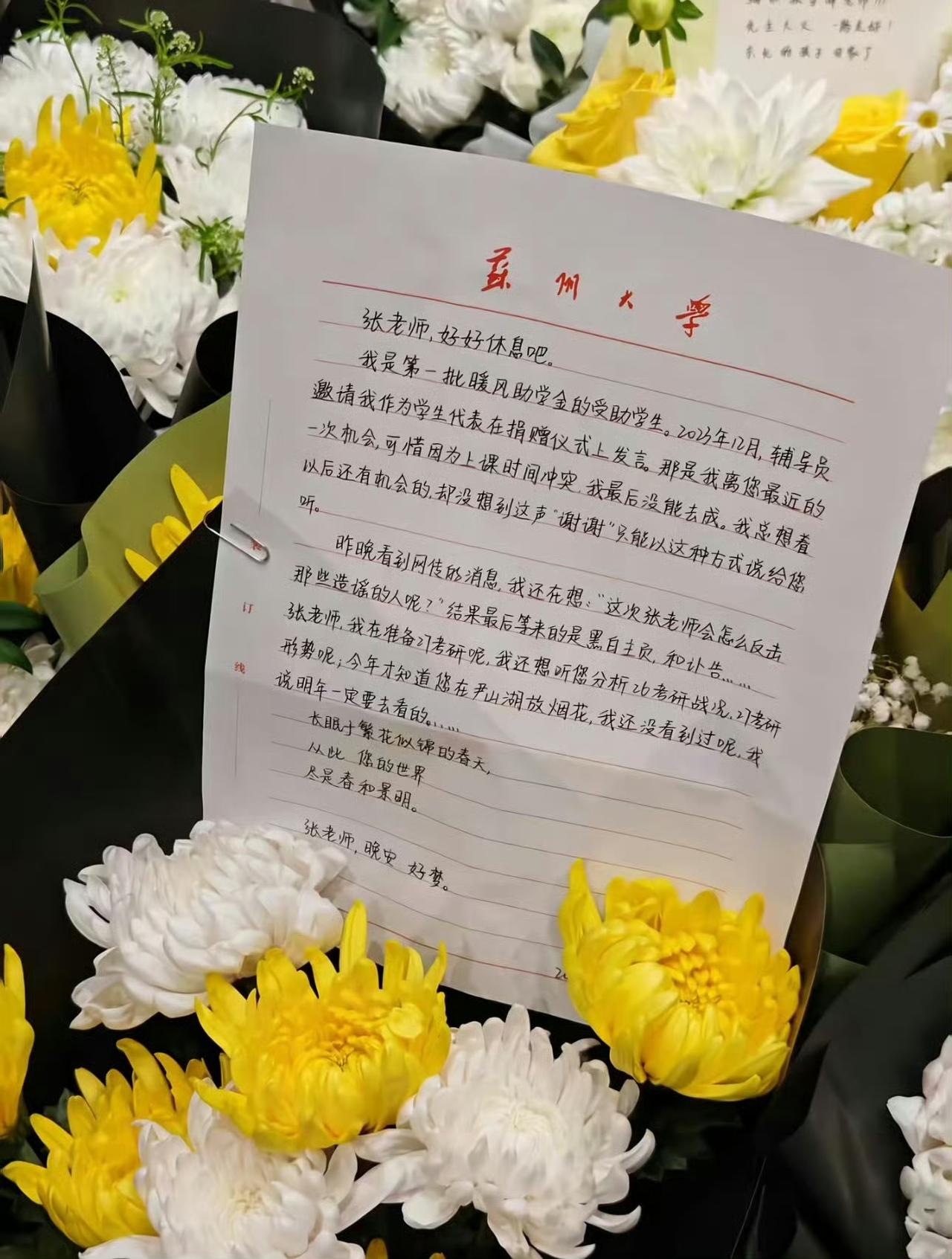 张雪峰公司楼下，花束挤挤挨挨地铺开了，像一片无声涌来的潮水。

每一束都带着卡片