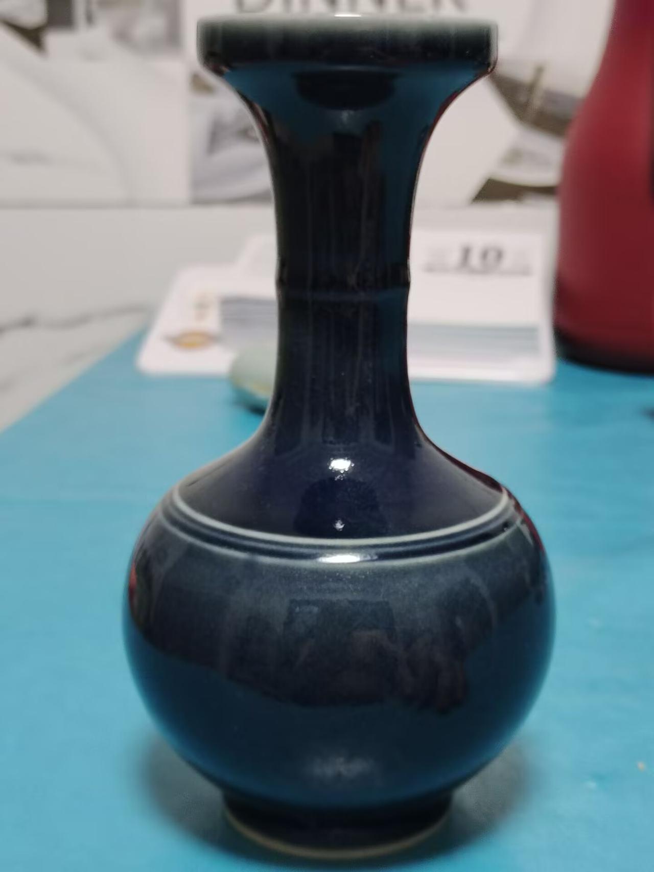 此为清中晚期仿雍正祭蓝釉弦纹盘口瓶，尺寸规整。颈肩双弦纹装饰，釉色浓郁沉稳，胎足