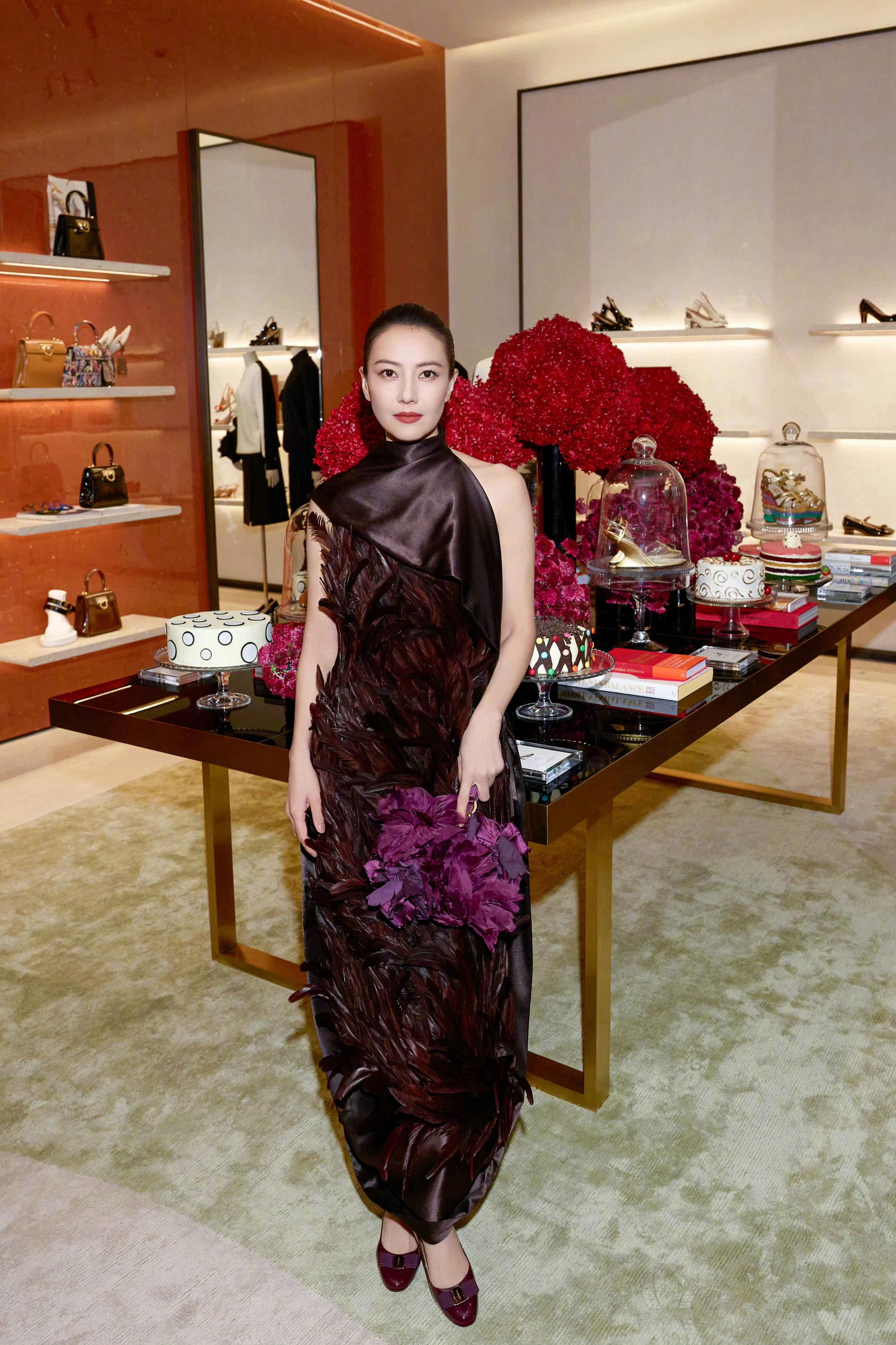 以一袭深咖色羽毛礼服亮相，缎面立领与层叠羽毛的碰撞，营造出高级复古质感。腰间紫花