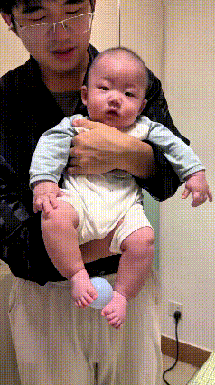 乖乖嘞，恁瞅瞅这个小宝贝，真是太招人喜欢了！年纪小小的，专注力可真不赖。爸爸抱着