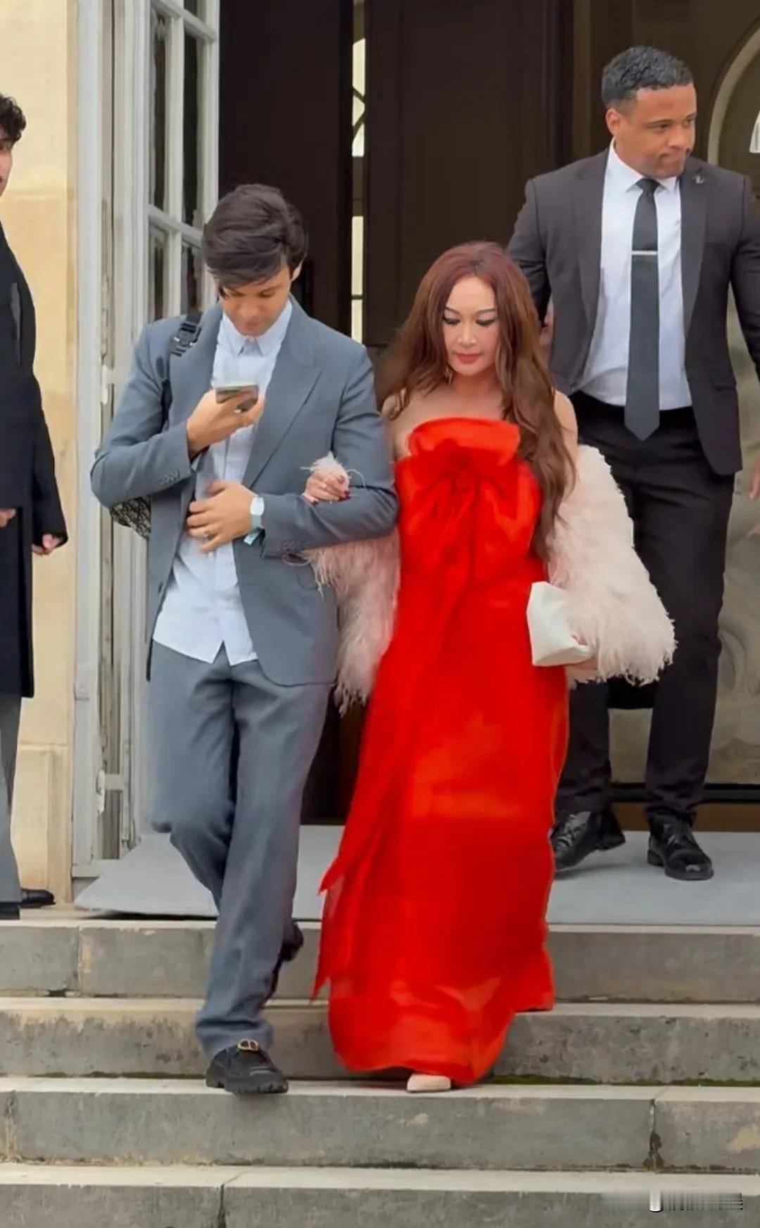 温碧霞现身巴黎看迪奥大秀，穿着一件大红色抹胸长裙，发色也染成了红色，肤色挺白的，