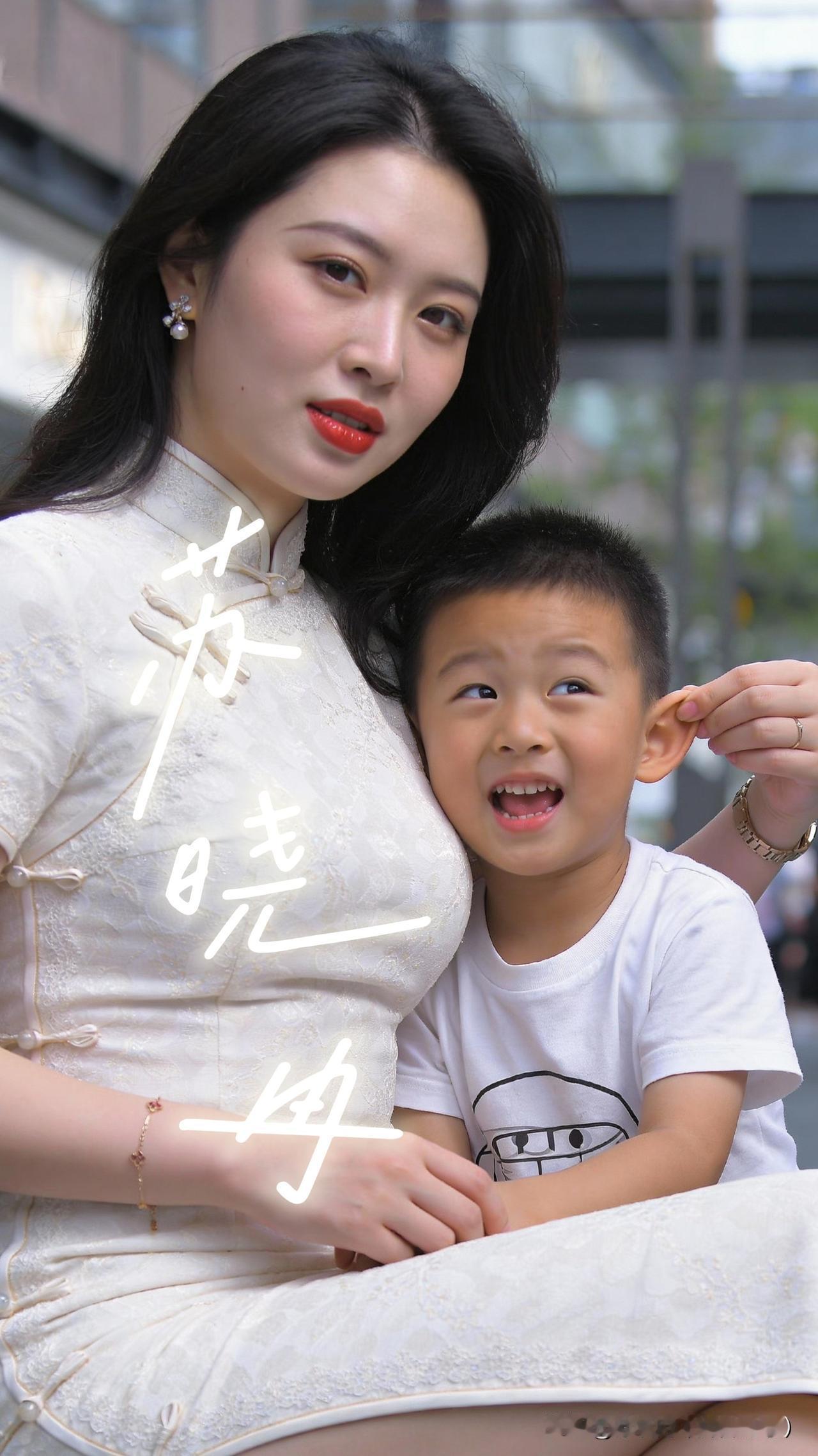 母子趣味互动，轻捏耳朵尽显亲子温情
城市商圈的休闲区域里，一位穿着素雅白色旗袍的