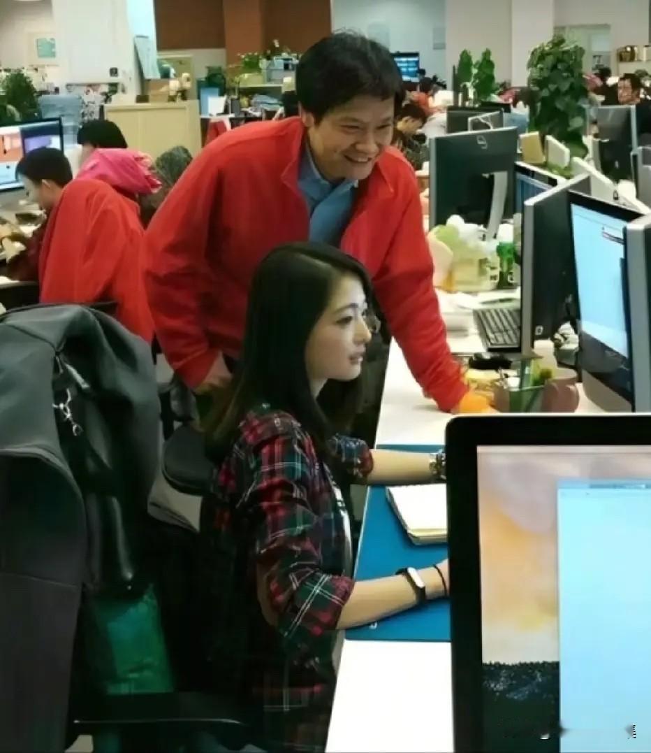 2014年前后，雷军在小米北京办公区俯身查看前端工程师张功的屏幕的一幕。张功，1