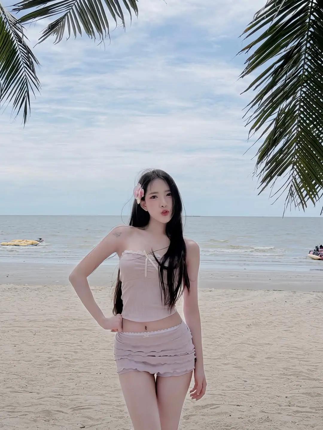 椰风裹着海的潮气，把粉调的松弛感揉进沙滩里。发丝沾了点咸湿的风，手里的青椰正坠着