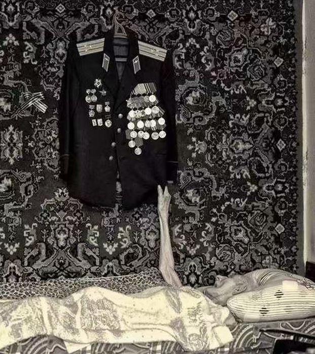 一名苏联老兵在去世前紧紧抓住了自己一生的荣耀，瘦小的身躯和挂满勋章的军装形成了鲜