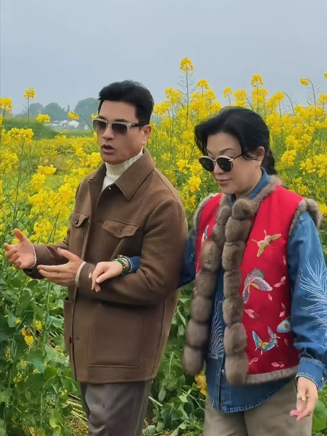 70岁吕良伟和老婆杨小娟到农村乡下看油菜花，夫妻俩挽手走在田间的泥泞小路上，他们